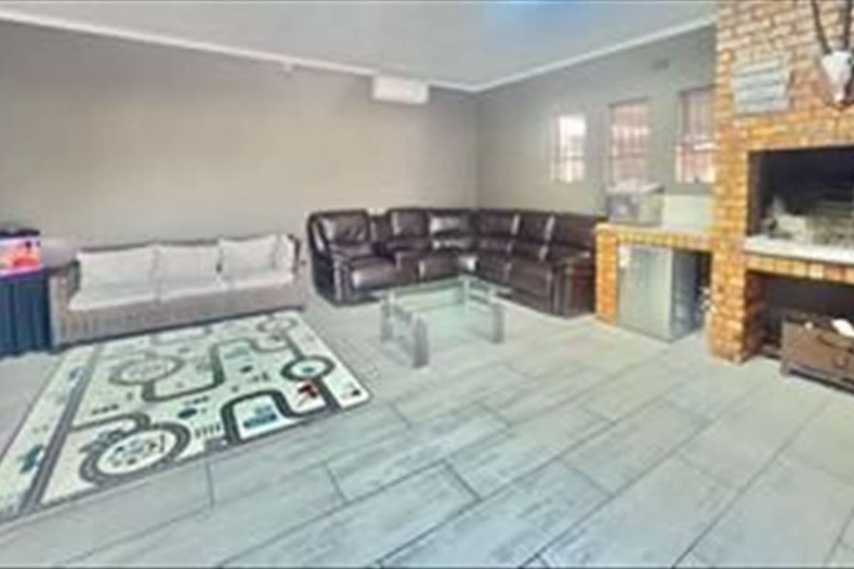 Spacious living area featuring a built-in brick fireplace, tiled flooring, and a wall-mounted air conditioning unit.