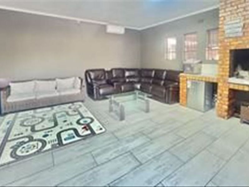 Spacious living area featuring a built-in brick fireplace, tiled flooring, and a wall-mounted air conditioning unit.