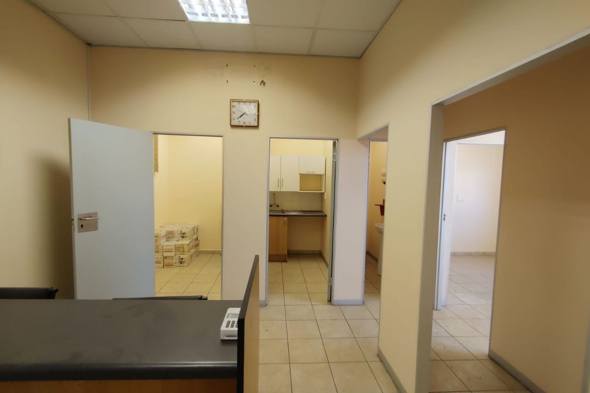 Commercial office space featuring tiled flooring, suspended ceilings, and access to a small kitchenette and multiple partitioned rooms.