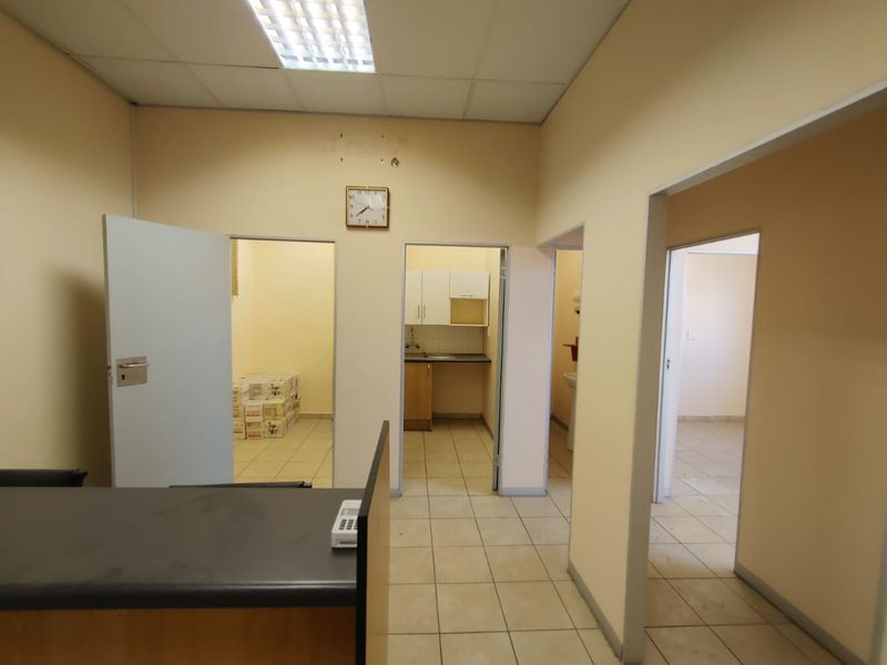 Commercial office space featuring tiled flooring, suspended ceilings, and access to a small kitchenette and multiple partitioned rooms.