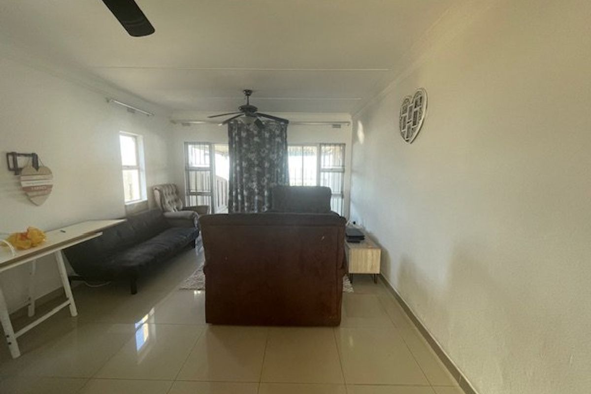 A living room featuring tiled flooring, a ceiling fan, and sliding glass doors leading to an outdoor area.