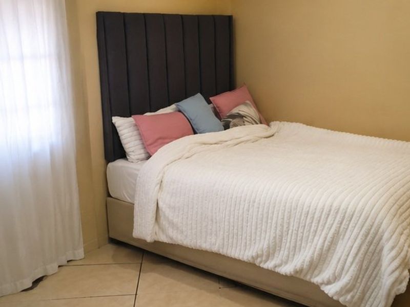 A cozy bedroom featuring neutral wall tones and tiled flooring, providing a comfortable and functional sleeping space.