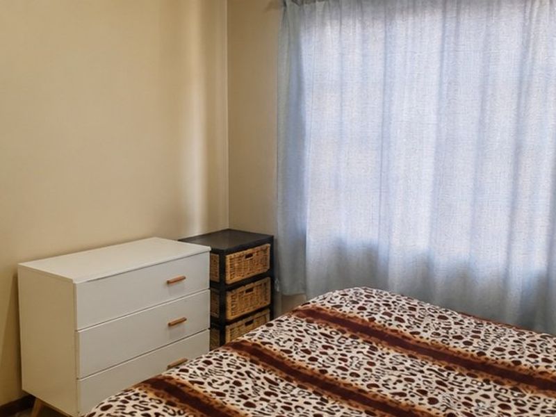 A standard bedroom featuring neutral wall finishes and a window with installed curtaining.