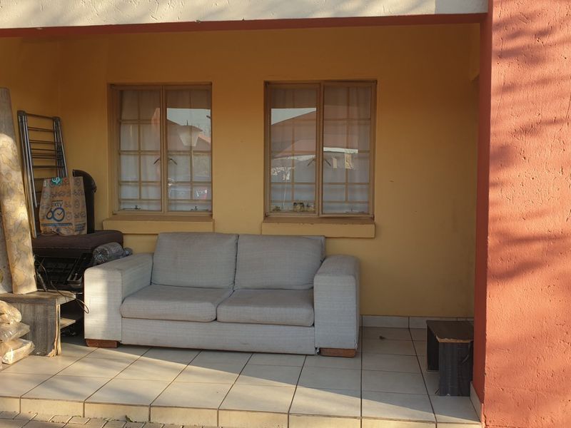 A covered patio area featuring tiled flooring and masonry pillars, providing an outdoor space with window access to the interior.