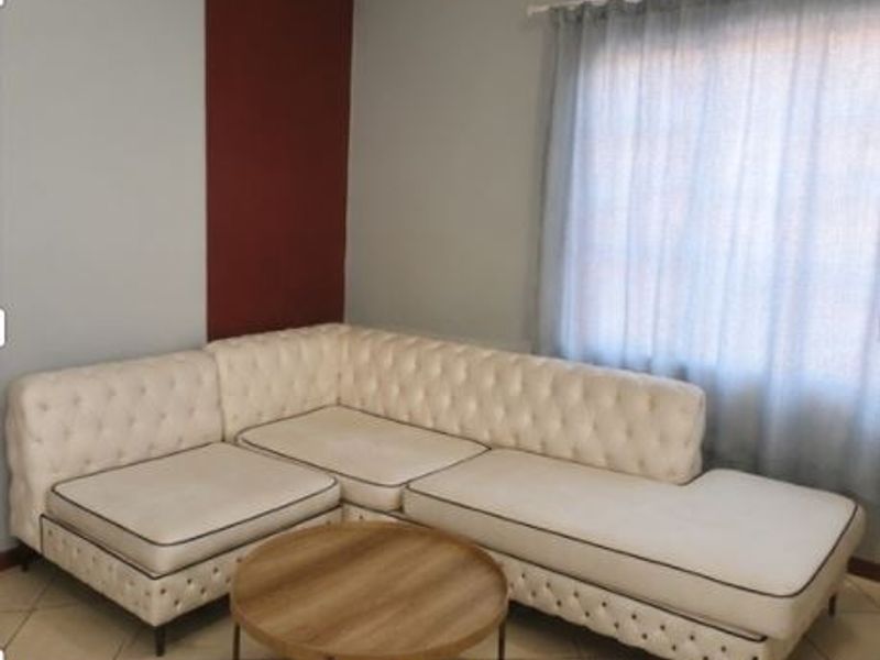 A living room area featuring tiled flooring and a window with a curtain rod, providing a neutral base for interior design.