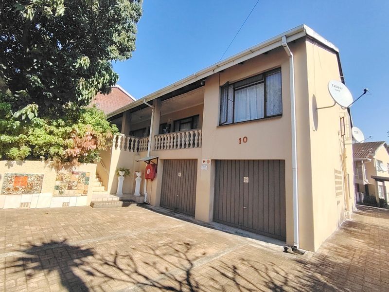 Front exterior view of a two-story residential property featuring a double garage, paved driveway, and an upper-level balcony with decorative balustrades.