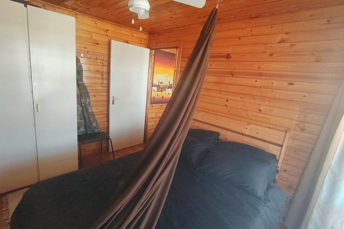 A bedroom featuring warm timber wall cladding, a ceiling fan, and built-in wardrobe storage.