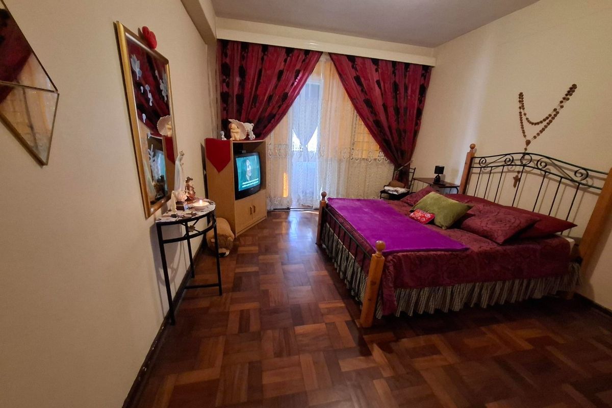 A bedroom featuring classic parquet flooring and a sliding glass door providing access to an outdoor area.
