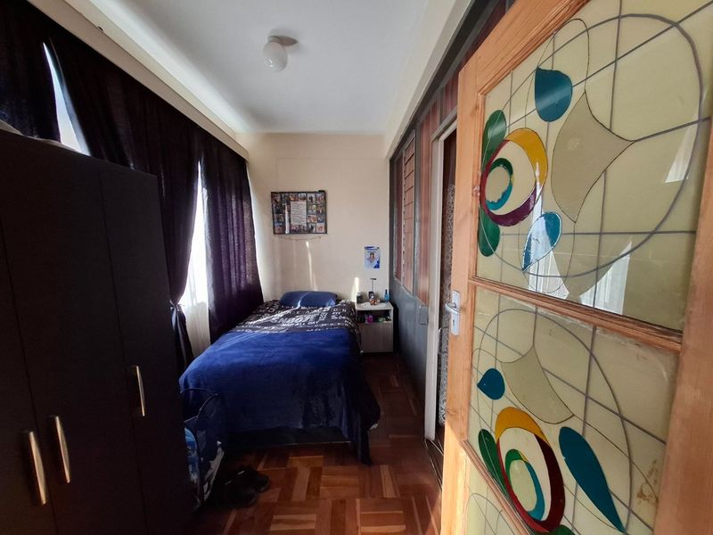 A bedroom featuring classic parquet flooring and a decorative stained glass door, providing a unique character to the living space.
