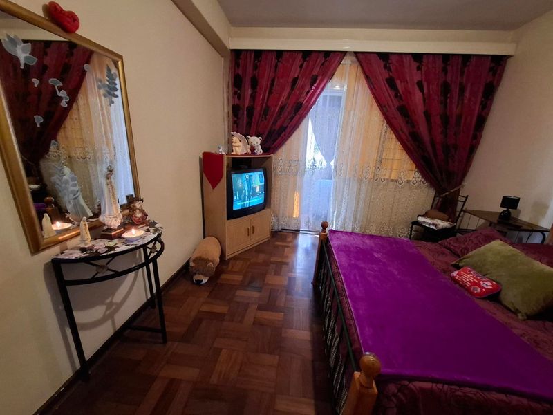 A bedroom featuring parquet flooring and a sliding glass door providing access to a balcony, allowing for natural light.