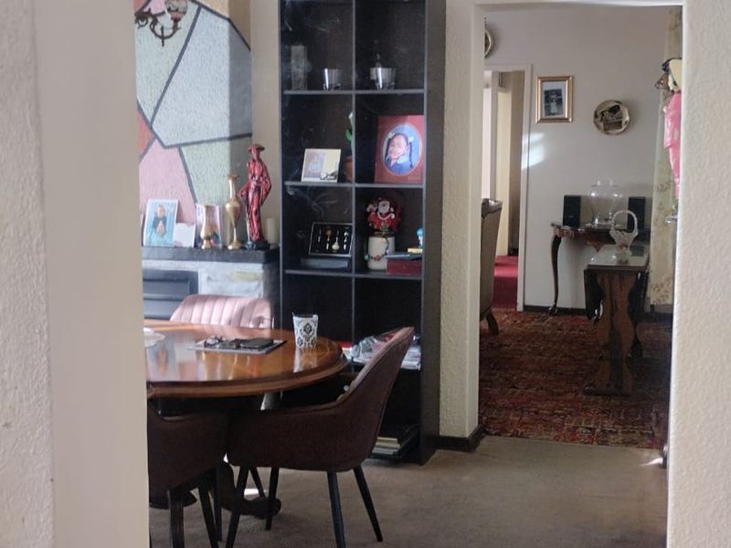 A view through an arched doorway into a living area featuring a fireplace and textured walls, with carpeted flooring throughout.