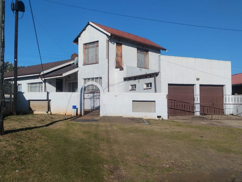 Front elevation of a two-story house featuring a double garage, gated pedestrian entrance, and a stucco facade with a tiled roof.