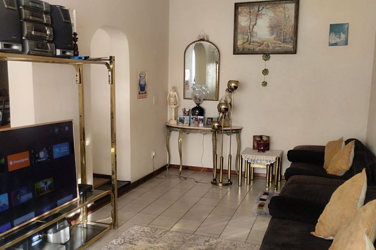 A living room featuring tiled flooring and an arched doorway leading to an adjacent space.