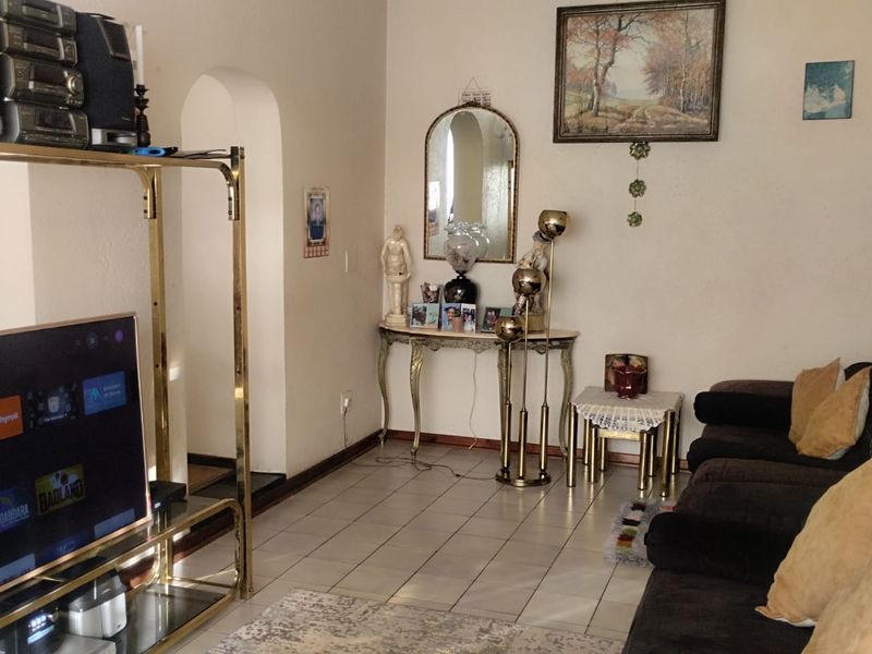 A living room featuring tiled flooring and an arched doorway leading to an adjacent space.