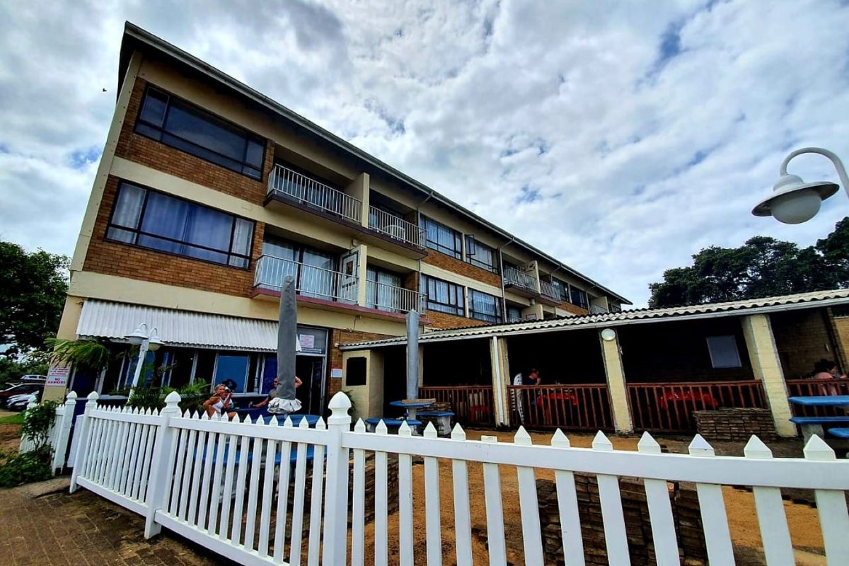 Rear view of a multi-story commercial building featuring brick facade, multiple balconies with metal railings, and a covered ground-floor patio area.