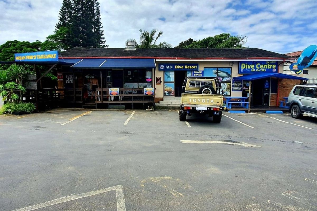 Commercial property frontage featuring a dive centre and takeaway shop with dedicated asphalt parking and timber deck access.