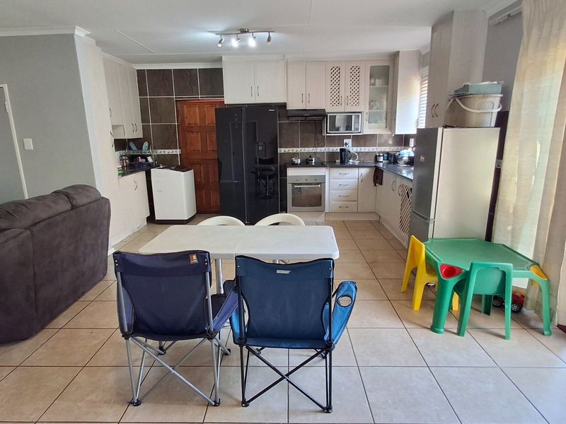 Open-plan kitchen and living area featuring tiled flooring, built-in cabinetry, and direct access to the outdoor area through a sliding door.