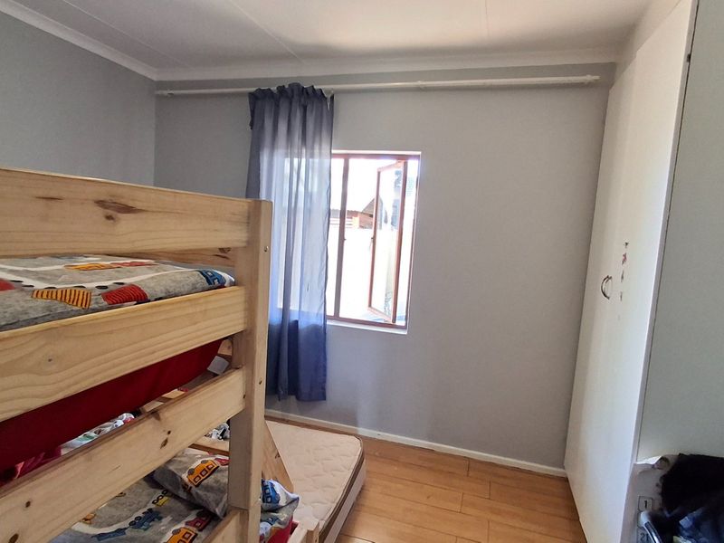 A bedroom featuring laminate flooring, a built-in wardrobe, and a casement window with a curtain rod.