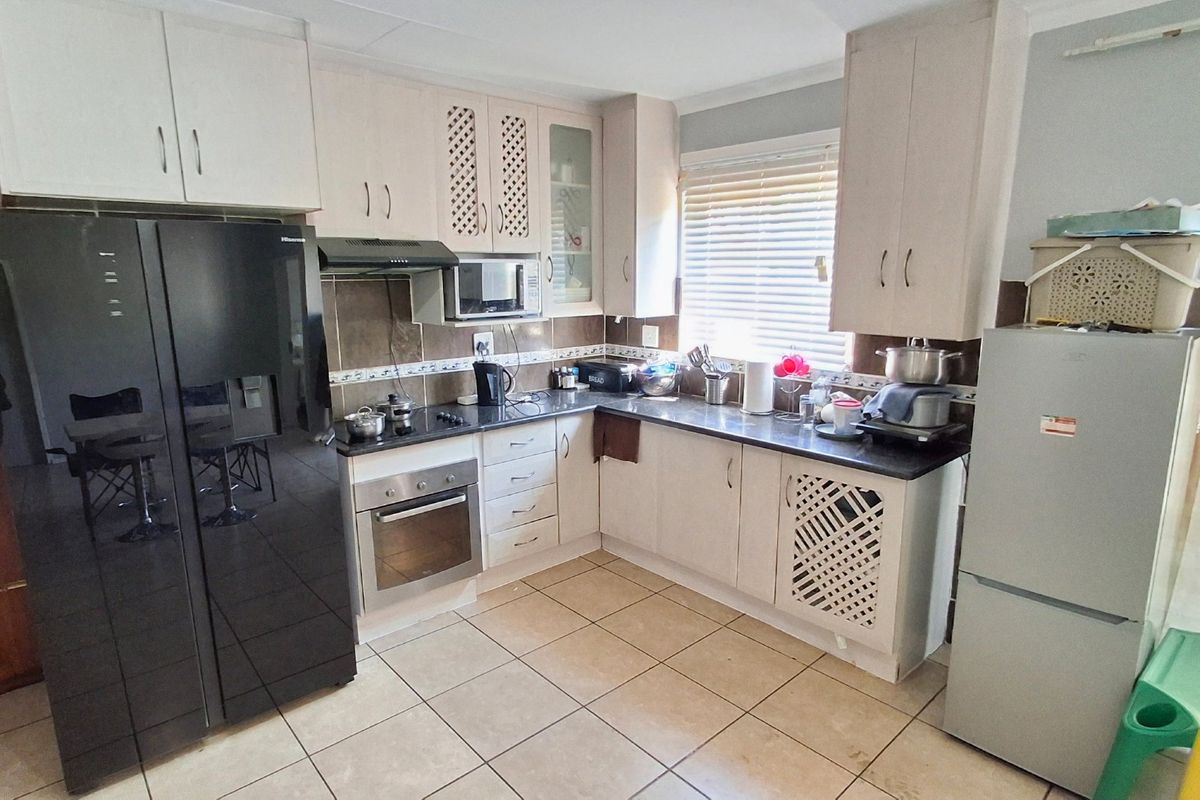 Functional kitchen featuring built-in cabinetry, laminate countertops, integrated oven and hob, tiled backsplash, and tiled flooring.