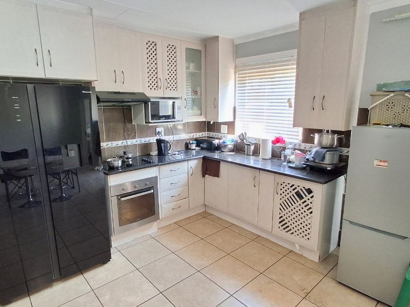 Functional kitchen featuring built-in cabinetry, laminate countertops, integrated oven and hob, tiled backsplash, and tiled flooring.