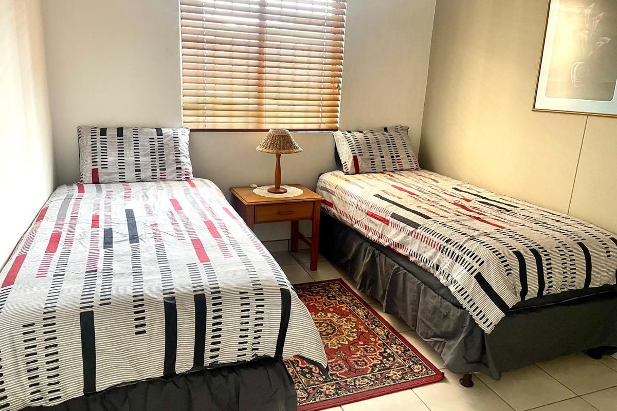A functional bedroom featuring tiled flooring and venetian blinds, providing a neutral space ready for personalization.