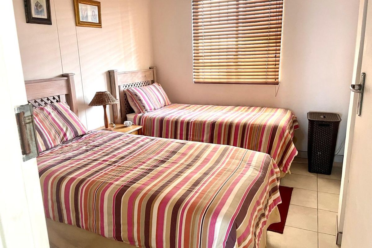 A functional bedroom featuring tiled flooring and venetian blinds, providing a simple and practical sleeping space.