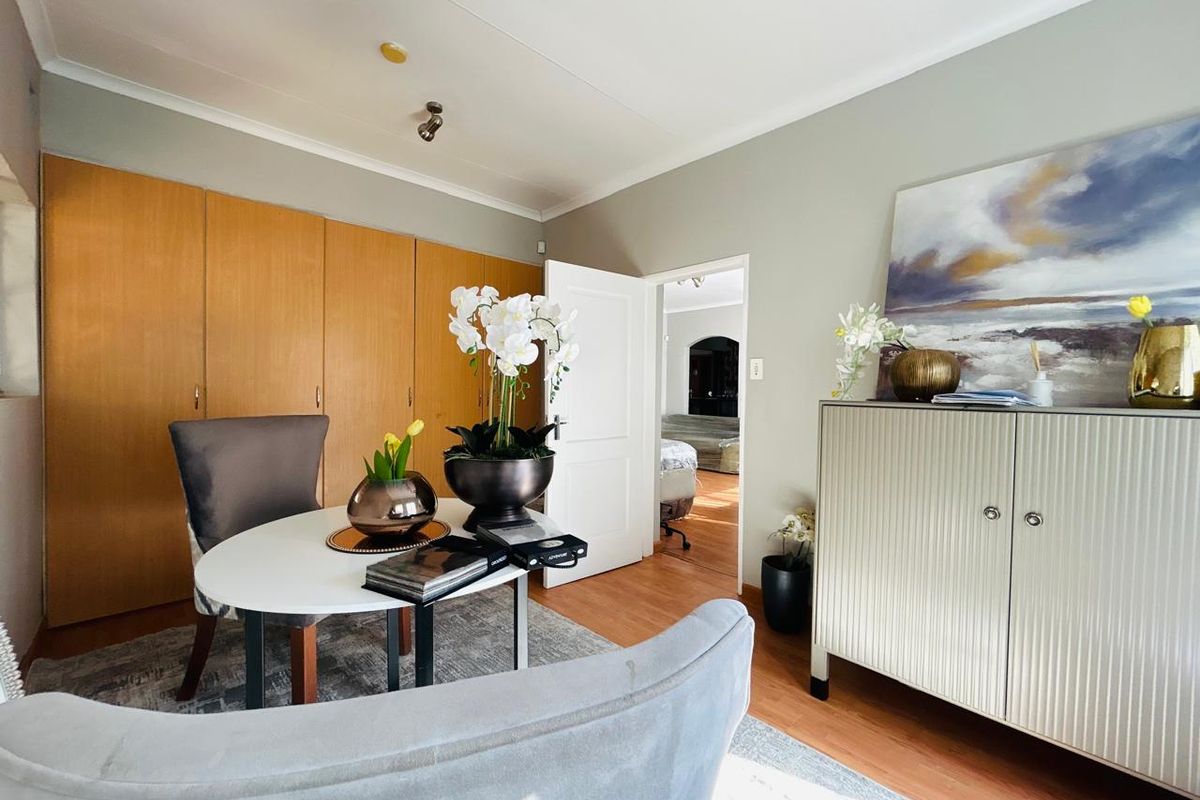 A well-maintained bedroom featuring extensive built-in wooden cupboards, laminate flooring, and neutral wall tones, offering a functional and comfortable living space.