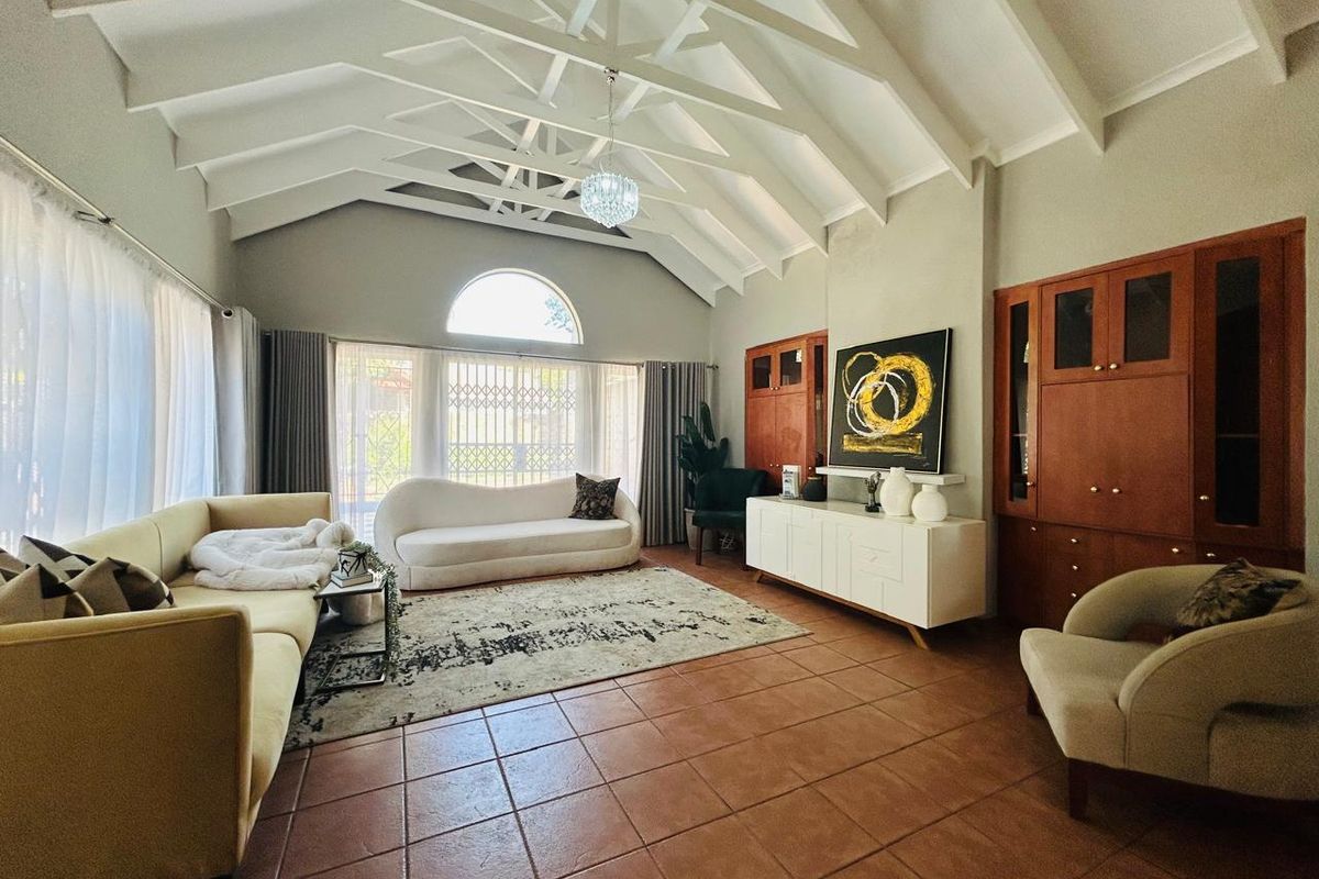 Spacious living room featuring a high vaulted ceiling with exposed trusses, tiled flooring, and custom built-in wooden cabinetry.