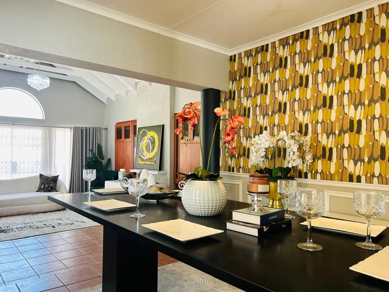 Spacious open-plan living and dining area featuring vaulted ceilings, decorative wallpaper, and tiled flooring with a seamless flow between connected living spaces.