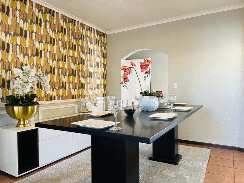 A dining room featuring a decorative patterned feature wall, built-in cabinetry, and a classic arched doorway leading to adjacent living spaces.
