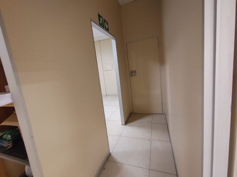 A functional commercial hallway featuring tiled flooring and internal access doors, providing connectivity between office or utility spaces.