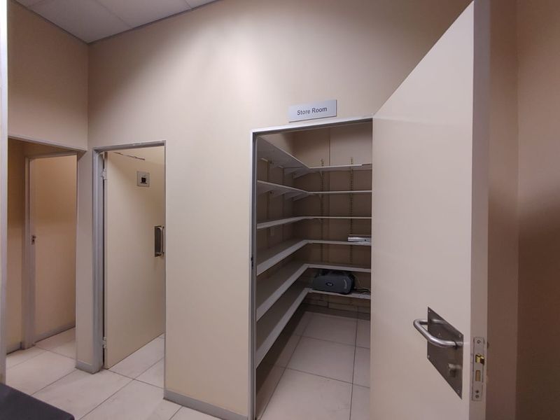 A functional commercial storage room featuring built-in shelving, tiled flooring, and a drop ceiling, providing organized space for inventory or supplies.