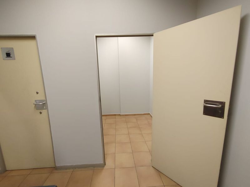 A functional commercial hallway featuring tiled flooring and access to multiple internal rooms.