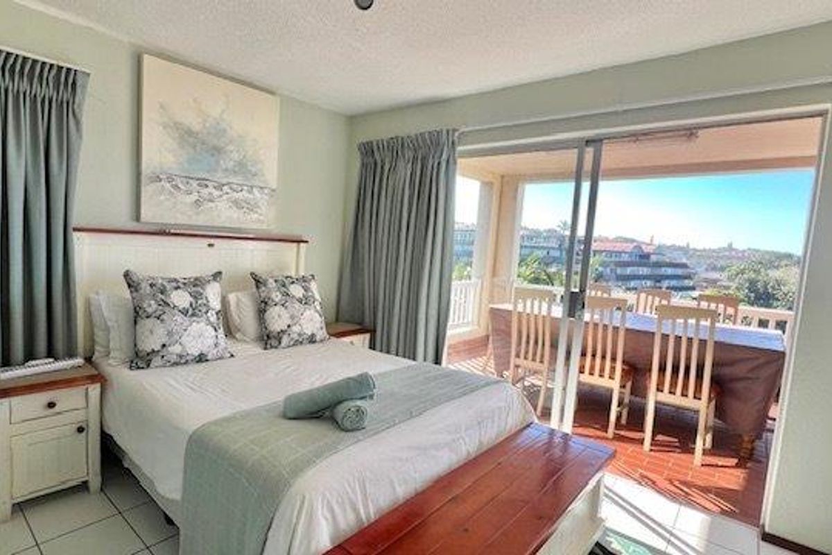 A bright bedroom featuring tiled floors and large sliding glass doors that provide direct access to an outdoor balcony area.