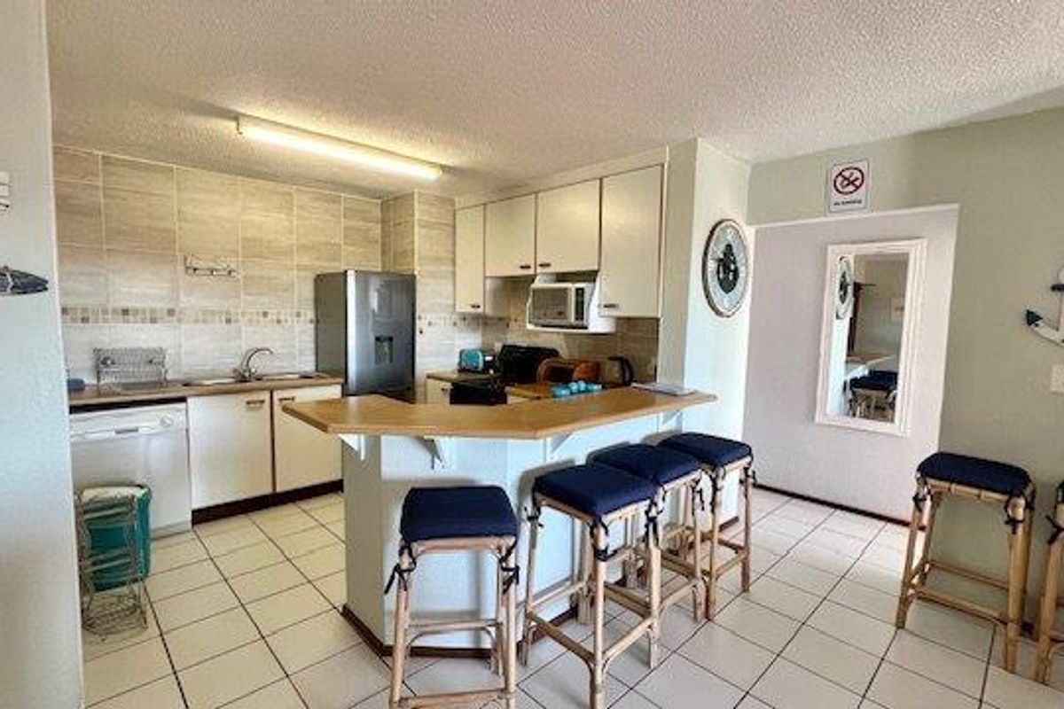A functional kitchen featuring built-in cabinetry, a tiled backsplash, a breakfast bar, and tiled flooring, offering a practical layout for daily use.