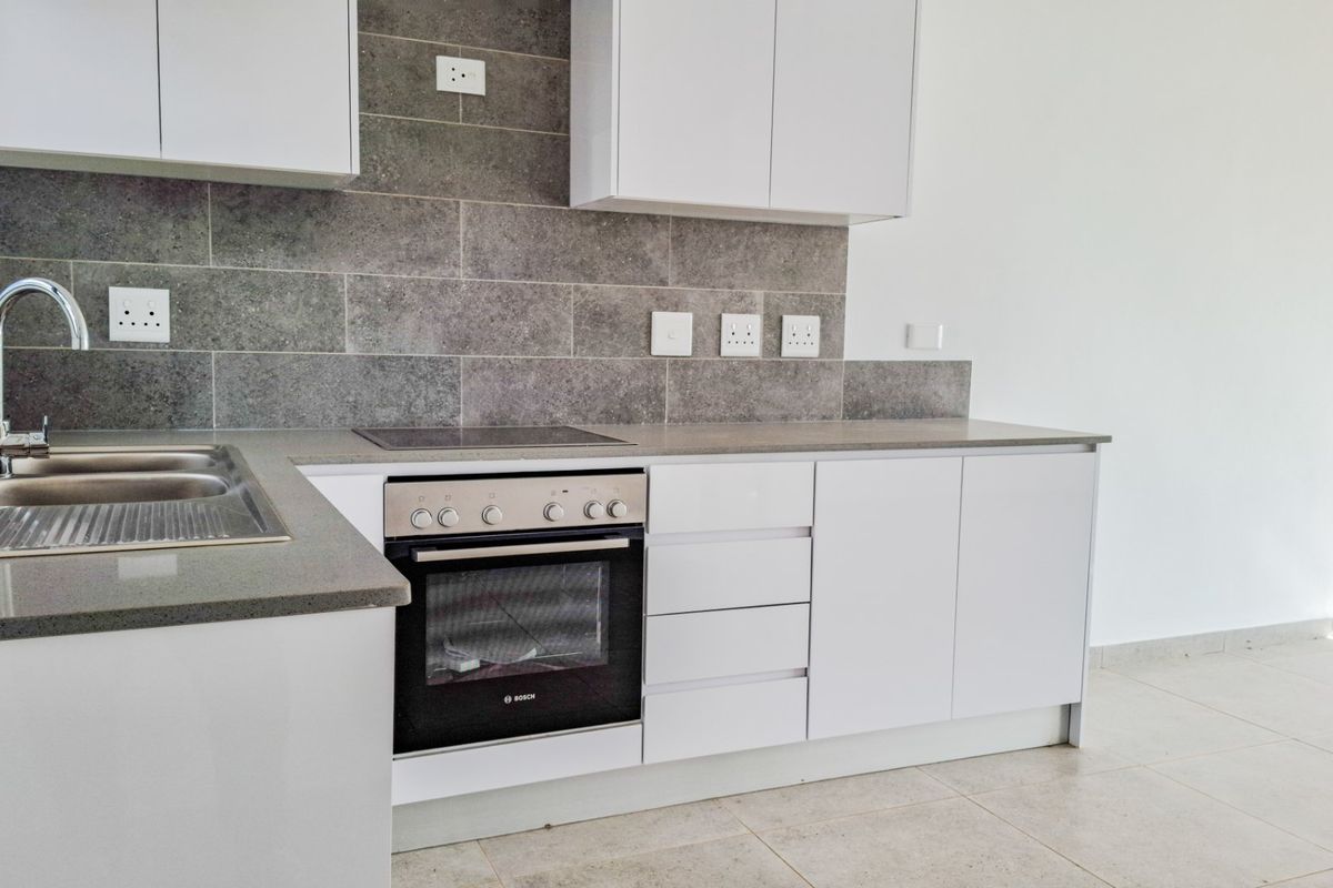 Modern kitchen featuring white cabinetry, stone countertops, a tiled splashback, and integrated Bosch oven and hob.