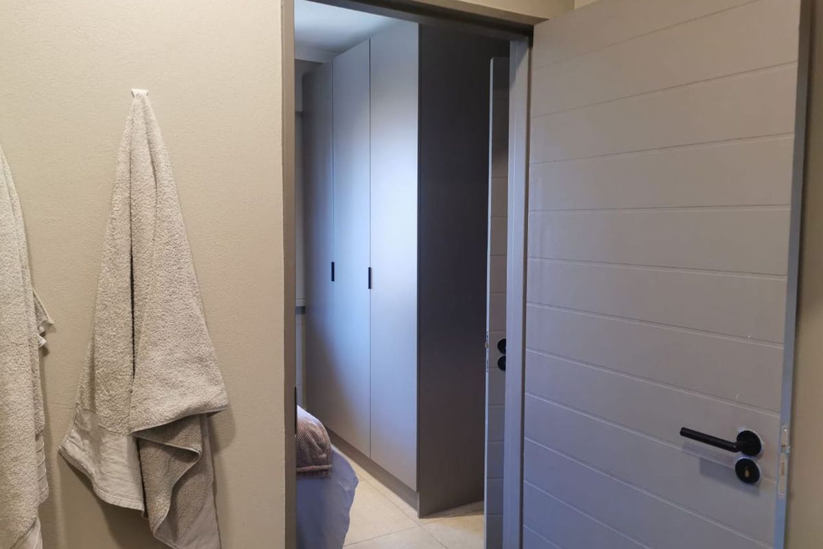 A view through a doorway into a bedroom featuring modern built-in cupboards and tiled flooring.