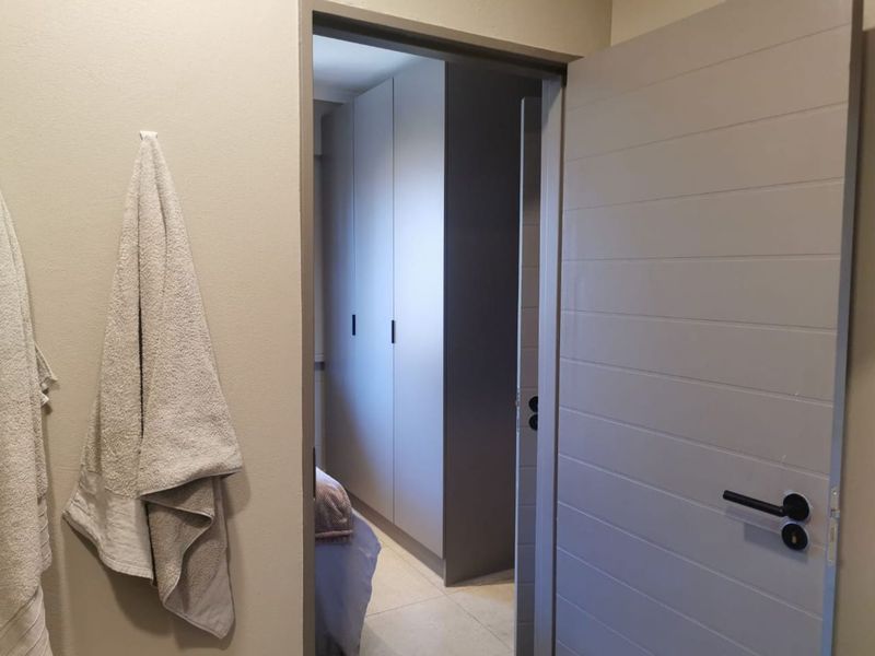 A view through a doorway into a bedroom featuring modern built-in cupboards and tiled flooring.