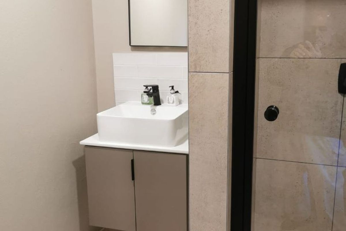 Modern bathroom featuring a floating vanity with a vessel sink, black fixtures, and a tiled shower enclosure with a glass door.