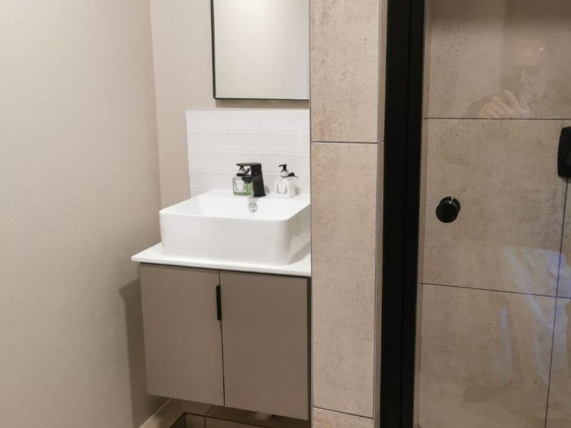 Modern bathroom featuring a floating vanity with a vessel sink, black fixtures, and a tiled shower enclosure with a glass door.