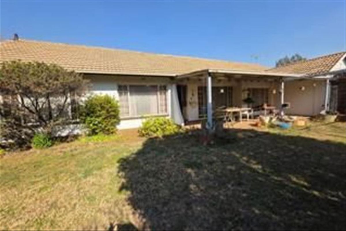 Rear view of the house featuring a covered patio area, tiled roof, and access to the garden through sliding glass doors.