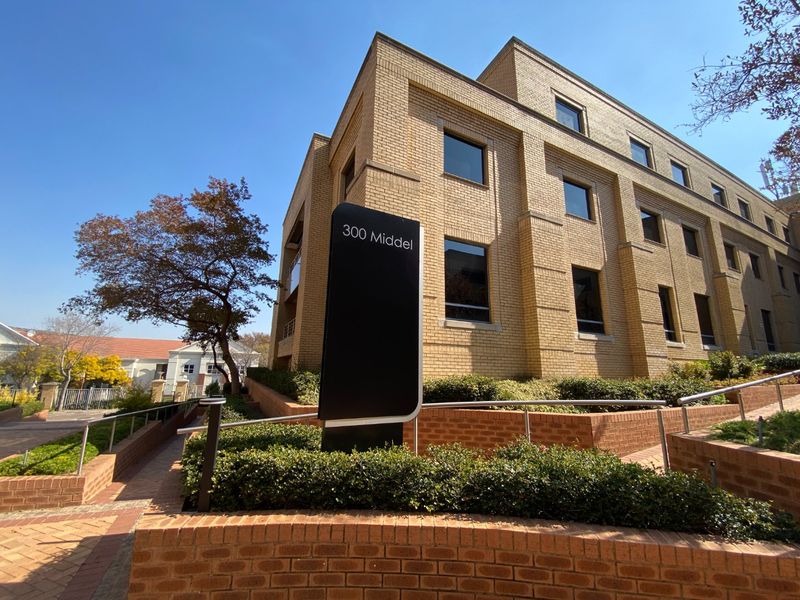 Exterior view of a commercial building featuring a brick facade, paved walkways, and a prominent signage pylon at the entrance.
