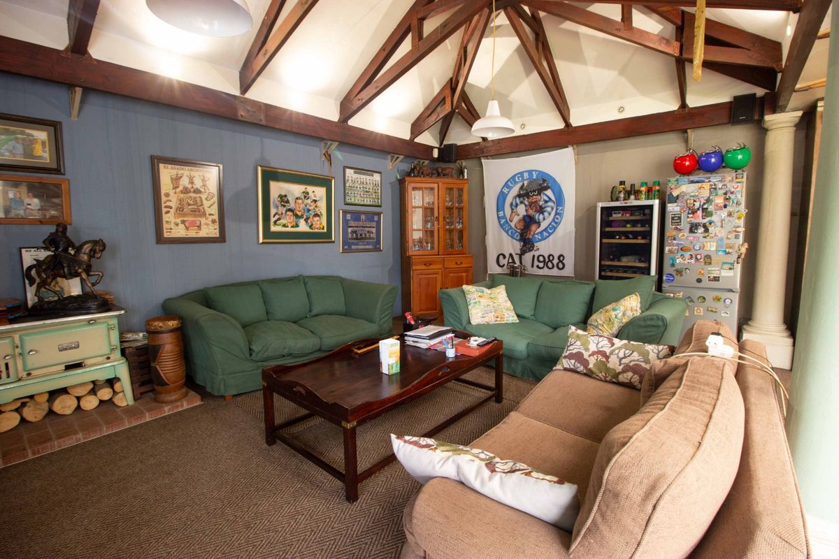Spacious living room featuring a high vaulted ceiling with exposed timber trusses and a built-in fireplace, offering a rustic and comfortable atmosphere.