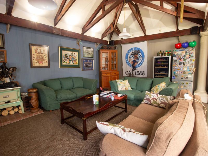 Spacious living room featuring a high vaulted ceiling with exposed timber trusses and a built-in fireplace, offering a rustic and comfortable atmosphere.