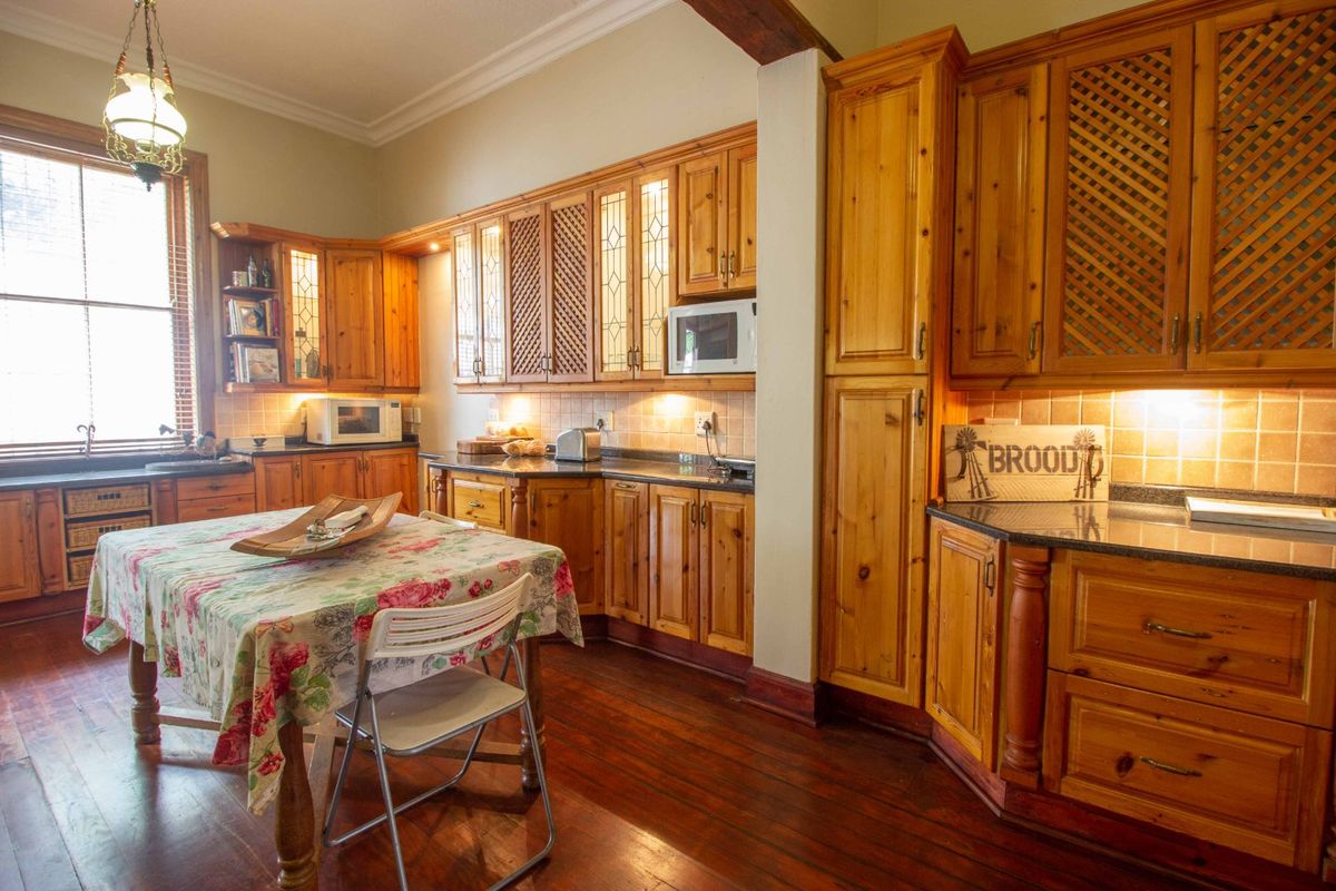 A traditional kitchen featuring extensive wooden cabinetry, granite countertops, tiled backsplash, and warm hardwood flooring, offering a classic and functional cooking space.