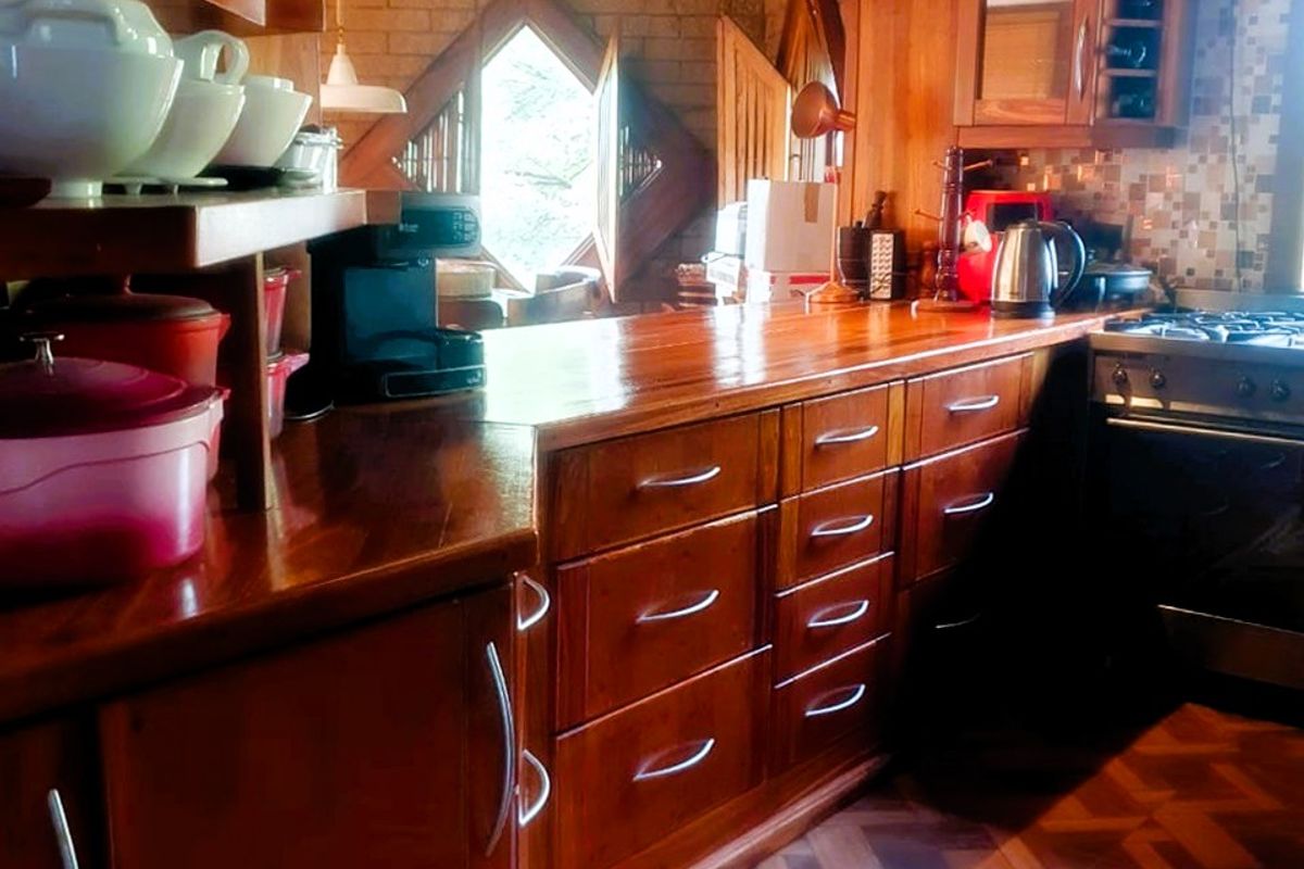 A rustic kitchen featuring extensive wooden cabinetry, wooden countertops, a mosaic tile backsplash, and a built-in gas cooktop with an extractor fan.