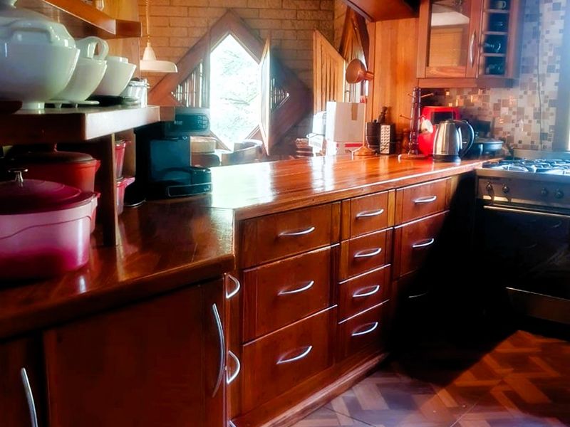 A rustic kitchen featuring extensive wooden cabinetry, wooden countertops, a mosaic tile backsplash, and a built-in gas cooktop with an extractor fan.
