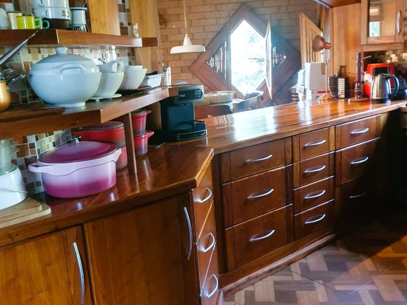 A rustic kitchen featuring extensive wooden cabinetry, solid wood countertops, a decorative mosaic backsplash, and a unique arched architectural detail.