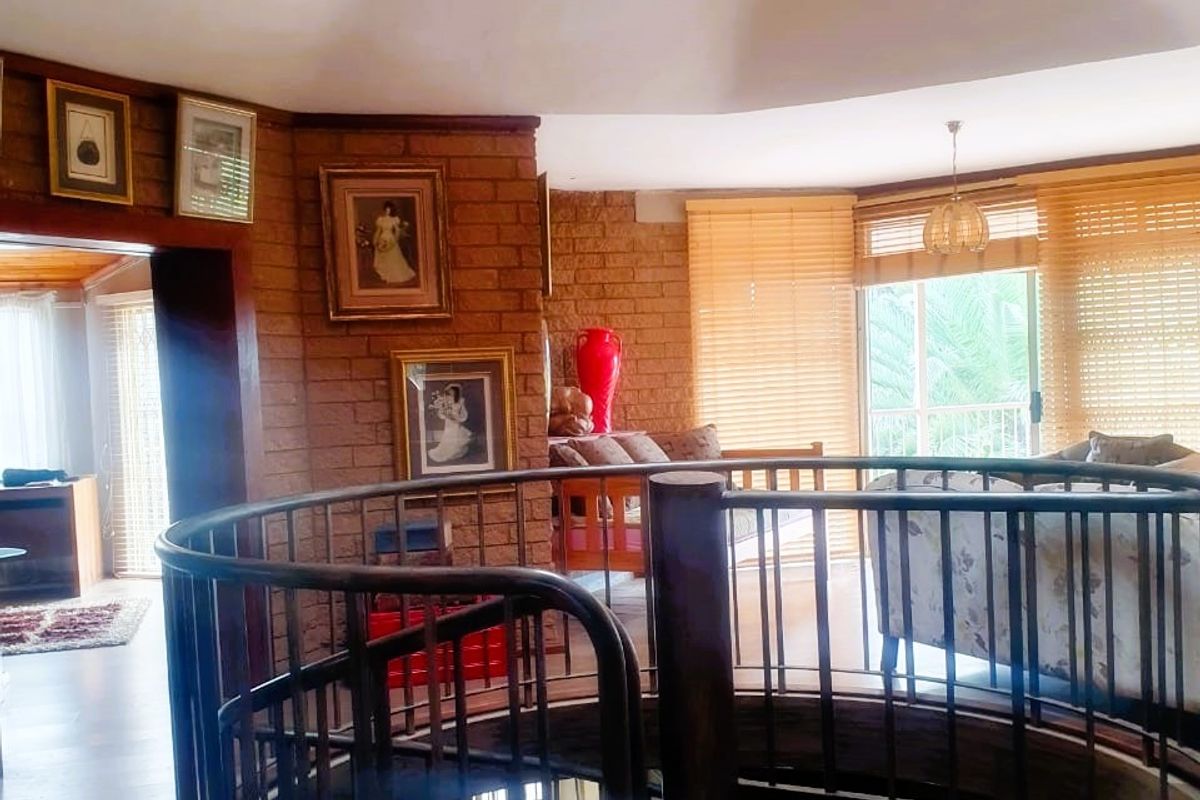 Spacious living area featuring a central spiral staircase, exposed brick walls, timber flooring, and a skylight providing natural light.