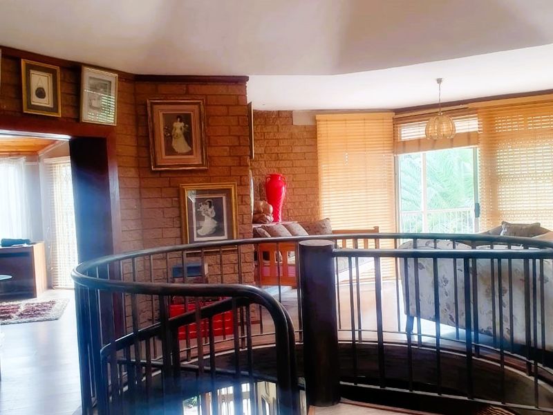 Spacious living area featuring a central spiral staircase, exposed brick walls, timber flooring, and a skylight providing natural light.